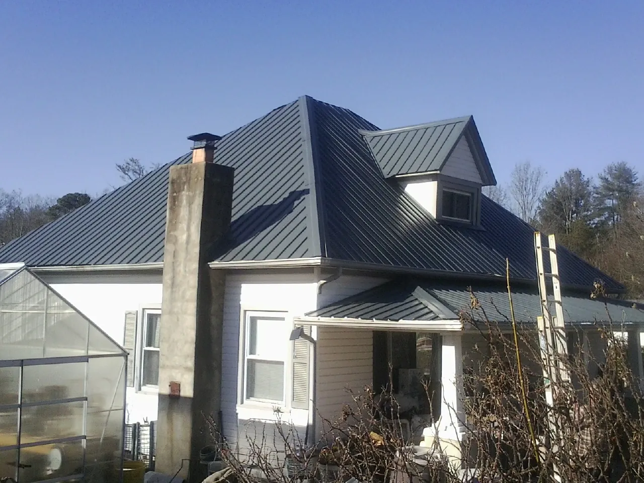 Dark blue standing seam metal roof on a white farmhouse with dormer — Slate & Tile Roof Repair by Roofing Brothers in Madill