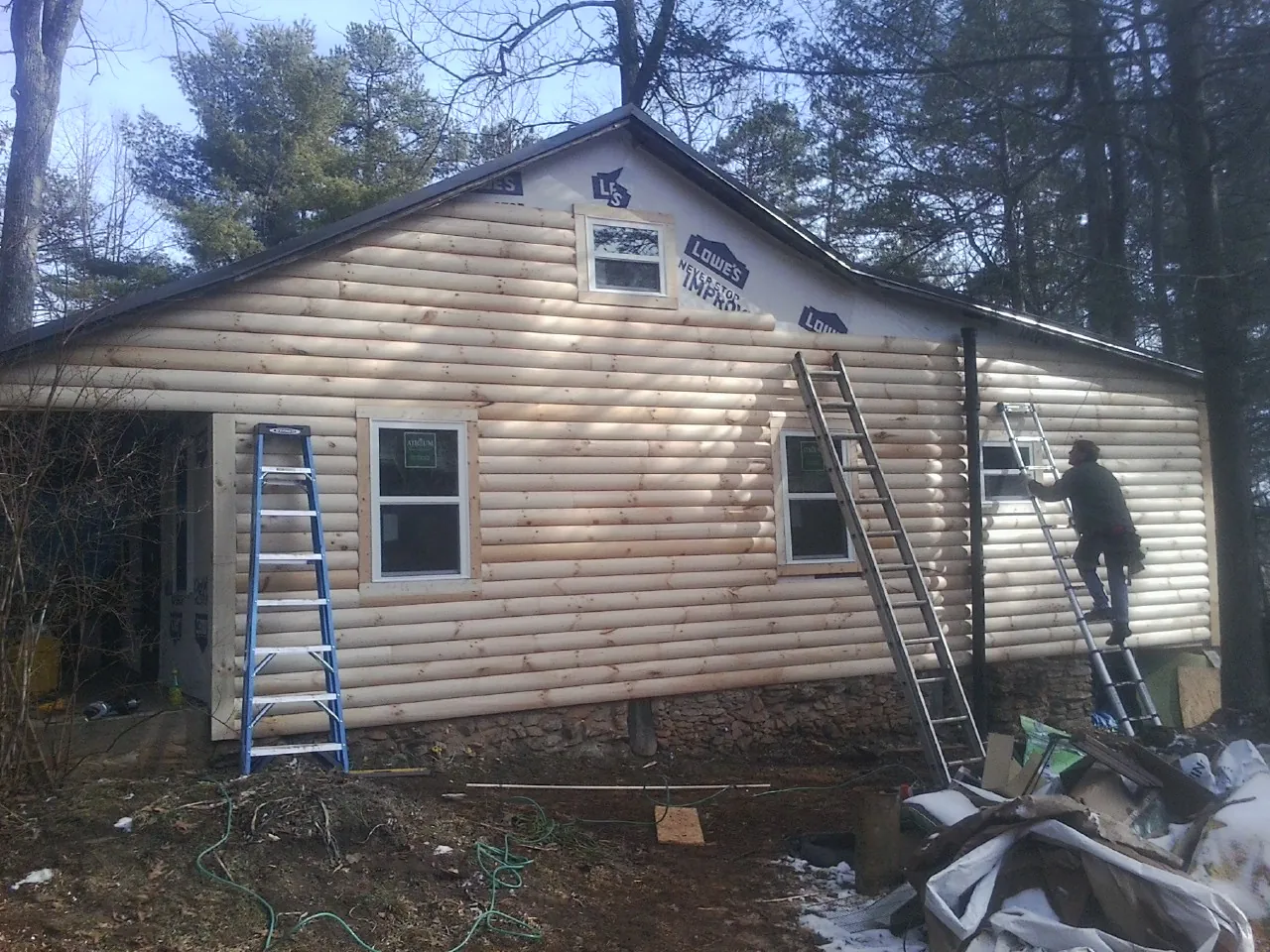 Ladders set against fresh log siding during an exterior remodel in Madill