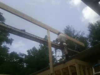 Carpenter setting a ridge beam over a new addition frame — Ice Dam Removal by Roofing Brothers in Madill