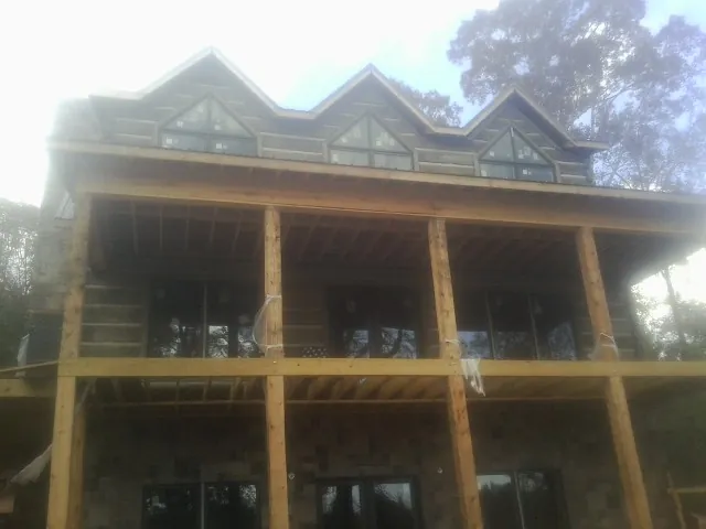 Dormers and porch framing on a large log home under construction — Roof Coating work by our crew in Madill