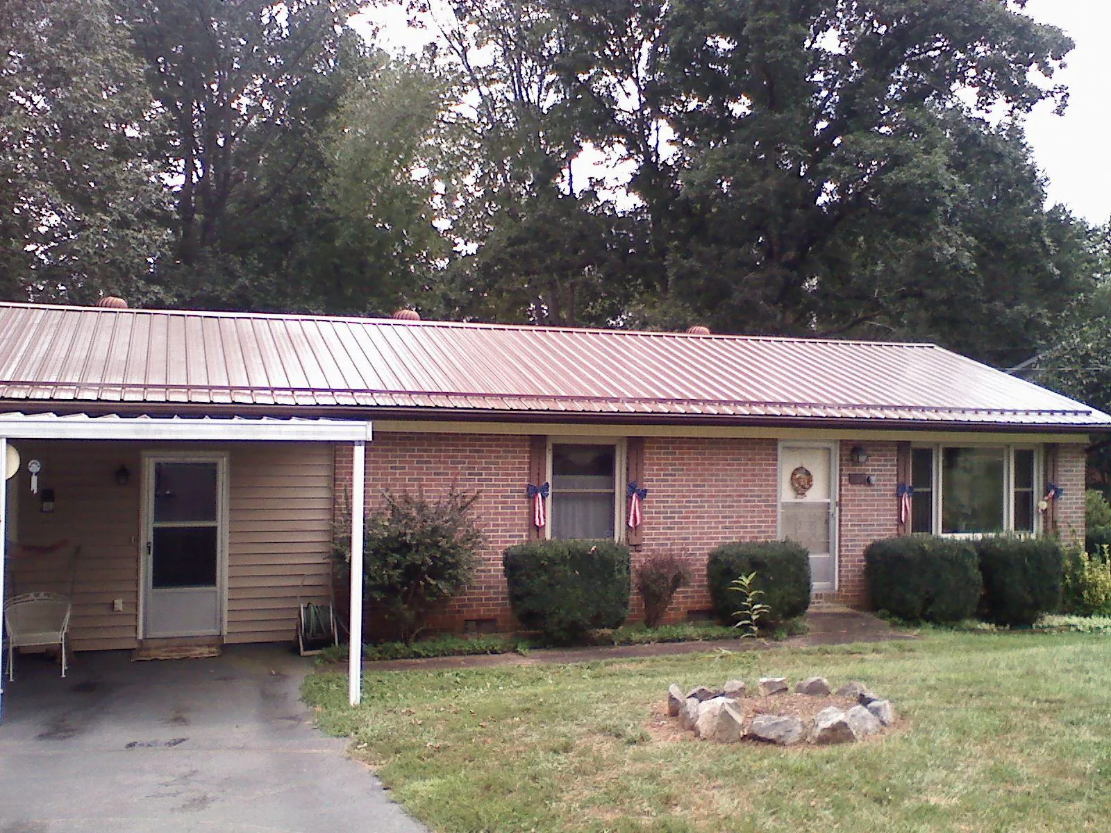 Bronze metal roof and carport on a brick ranch home — Roof Repair work by our crew in Madill