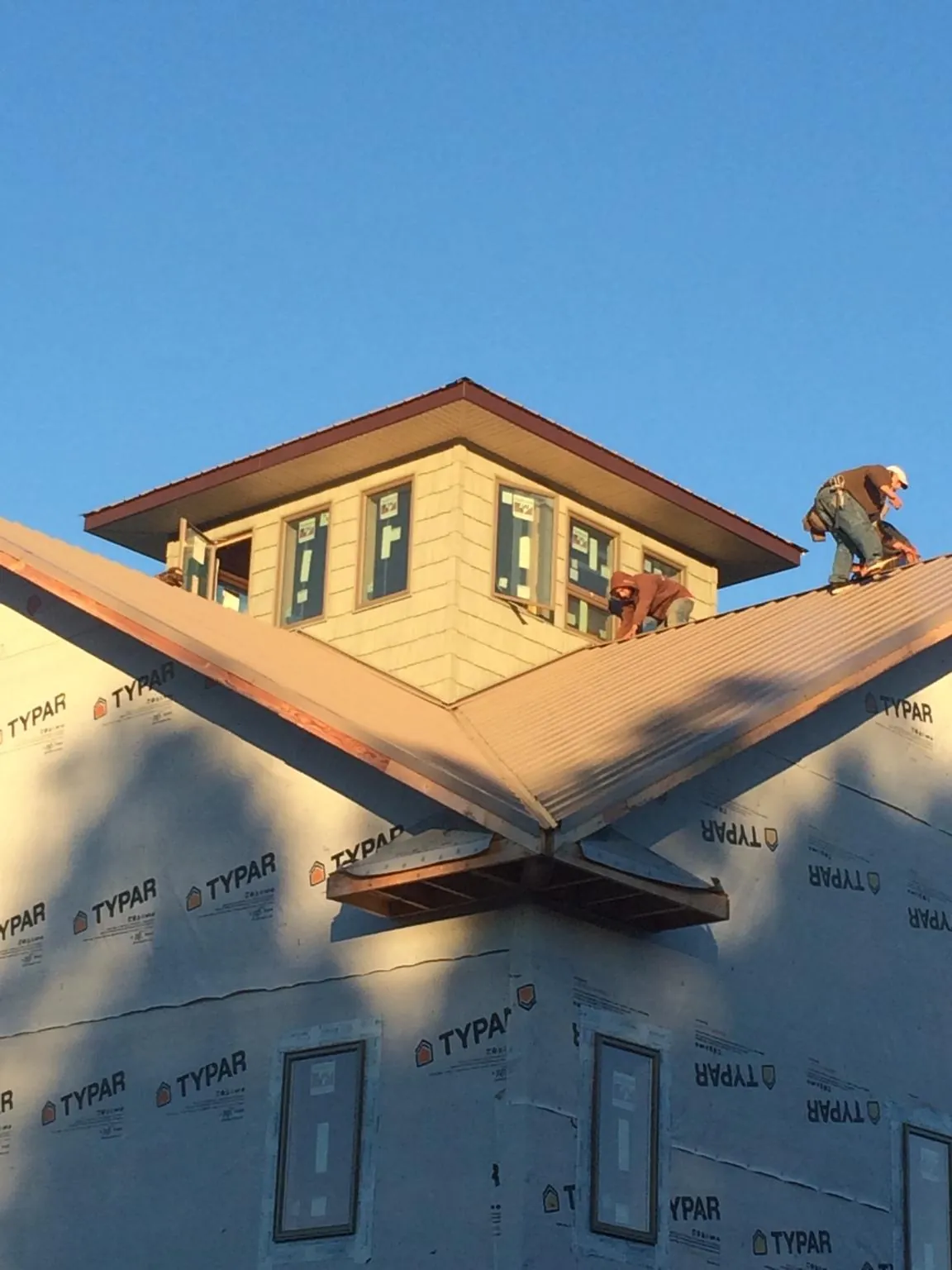 Roofers working around a rooftop cupola on a new metal roof at sunset — Roof Waterproofing in Madill by Roofing Brothers